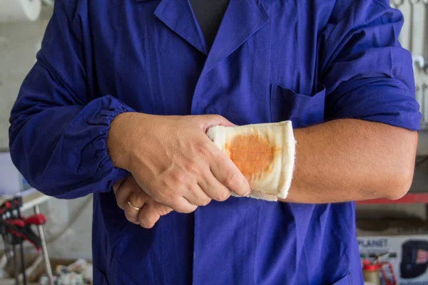Image of a handyman with a bandaged wound on his arm. Reference to accidents at work