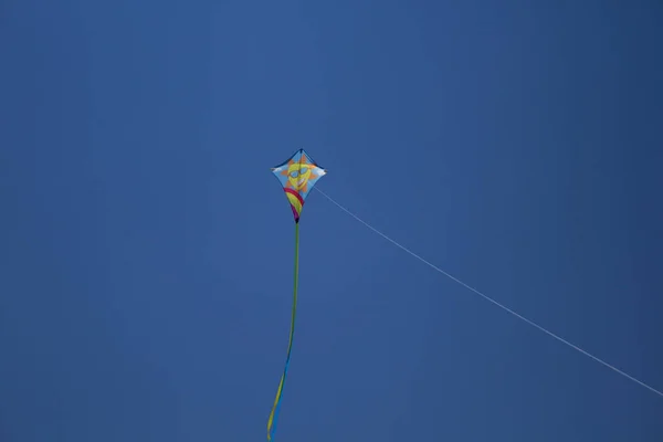 Изображение Цветного Воздушного Змея Летящего Высоко Небе Рисунком Улыбающегося Солнца — стоковое фото