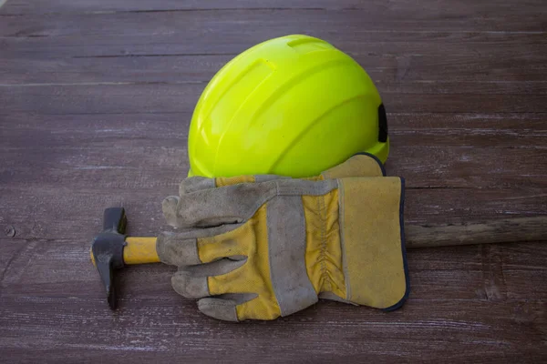 Image of a mason's hammer, hard hat and work gloves. Reference to manual work and accidents at work
