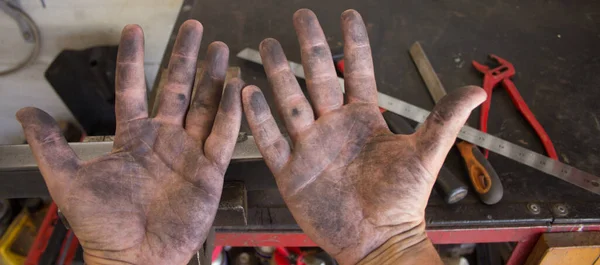 Image of the dirty hands of a blacksmith working in his workshop with the tools of the trade background. Do it yourself work. Dirty hands smell of dignity