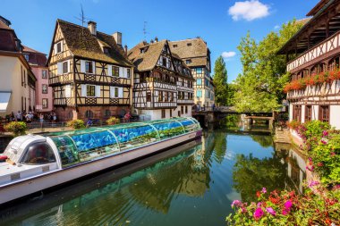 Strasbourg, France - 15 August 2020: Tourist boat on Ill river in the historical center of Strasbourg, Alsace, France. Boat trips are popular touristic attraction in the Old town of Strasbourg city.