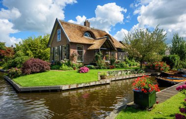 Hollanda 'nın huzurlu Giethoorn köyündeki su kanalı ve geleneksel tuğla evler güneşli bir yaz gününde