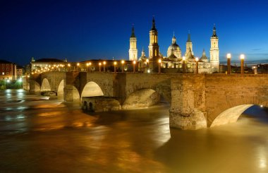 Zaragoza şehri, Ebro nehri üzerindeki ortaçağ taş köprüsü Puente de Piedra manzarası ve geceleri Sütunun Efendisi İspanya Katedrali.