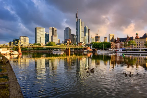 フランクフルトは ドイツの劇的な日の出の光の中 主要川を反映した主要都市の金融街のスカイラインです — ストック写真