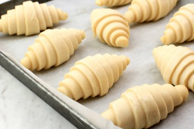 Pofuduk Yapraklı Çiğ Kruvasan Çöreğini Fırında Pişirmeye Hazırlanmak İçin Bir Kart Tabağı ve Kağıt Çarşafta Kapatın. Bu bir Buttery, Flaky Pastacılık..