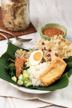 Nasi Pecel. Geleneksel Java Pirinç Buharlı Pirinç Tabağı Sebze Salatası, Fıstık Sosu Sosu, Tempeh, Tofu Fasulyesi ve Peyek Krakerleri. Pecel Madiun En Popüler Varian