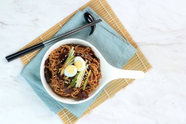 Top View Jajangmyeon veya JJajangmyeon, Black Sauce ile Kore Noddle 'ıdır. Üstünde bıldırcın, salatalık, susam tohumu ve taze soğan var. Boşluğu Sağda Kopyala, Kapat