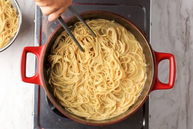 Top View Boiling Korean Instant Noodle or Spaghetti Pasta  on Red Pan, Home Cooking Activity