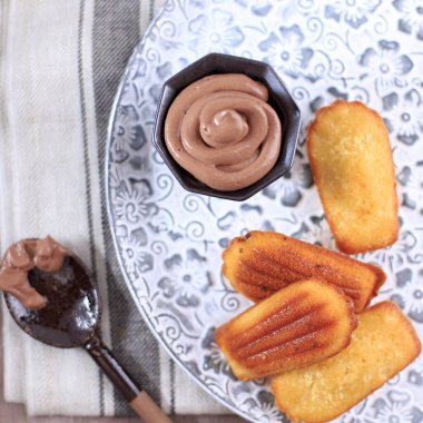 Top View Madeleine on Rustic Tray, Homemade Traditional French Small Cookie with Shell Shape on Rustic Background. Served with Chocolate Sauce