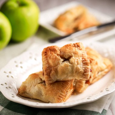 Puff Pastry Apple Pastry Turnovers for Dessert on a White Plate and Wooden Table. Made from Frozen Puff Pastry with Apple Filling