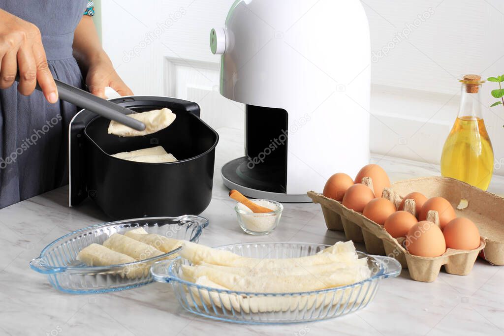 Cooking Proces Using White Air Fryer for Healthy Cooking in the Kitchen. Woman Hand Put Fritters Lumpia to the Air Fryer Tray