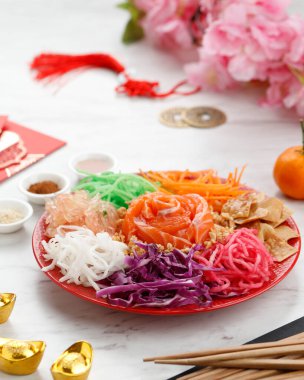 Çin Refah Mutfağı, Yee Sang veya Refah Fırtınası 'nın lezzetli ve renkli bir görüntüsü. Havuç şeritleri, mor lahana, çiğ somon, yer fıstığı, börek, Pomelo