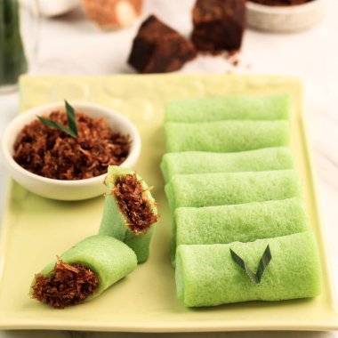 Dadar Gulung, Glutinous Rice, Grated Coconut ve Palm Sugar 'dan geleneksel çerez. Malezya, Endonezya ve Singapur 'da popülerdir. Beyaz Ahşap Arkaplanda Yeşil Tabakta Servis
