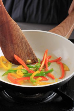 Kızarmış Paprika 'yı Kara Pan' da karıştırmak, Mutfakta Pişirme Süreci Kore Japchae, Çin Biberi veya İtalyan Peperonata gibi lezzetli yemekler yapmak