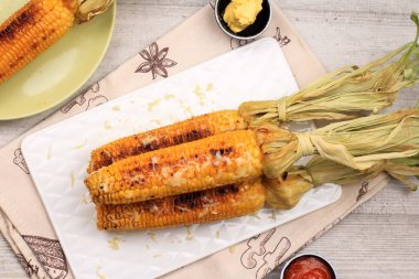 Tereyağlı ve doğranmış mozarellalı ızgara mısır. Beyaz Tabakta Servis