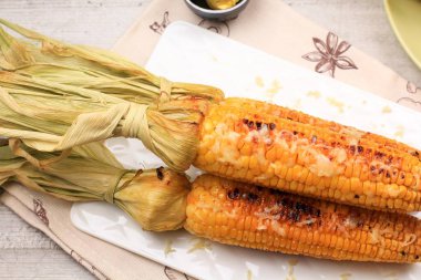 Tereyağlı ve doğranmış mozarellalı ızgara mısır. Beyaz Tabakta Servis