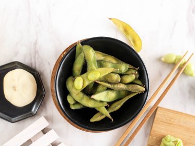 Siyah Bowl 'da buharda pişmiş Edamame, Mermer Beyaz Masa üstünde. Boşluğu Kopyala
