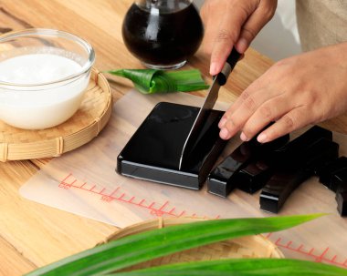 Kadın eli dilimlenmiş Cincau Hitam veya Black Grass Pudingi küp şekerler, sağlıklı yiyecek konsepti