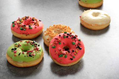 Assorted  Doughnut with Colorful Sprinkle Isolated on White Background, Copy Space for Text on Grey Cement Background clipart