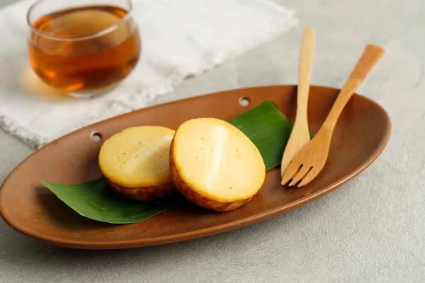 Kue Lumpur Kentang  or Potato Mud Cake, Indonesian Traditional Cake made from Potato, Sweet and Soft Texture. Served on Brown Ceramic Plate with Tea