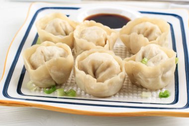 Buharda pişirilmiş Mandu Dumpling, geleneksel Kore Dim Sum Sokağı Yemeği. Çin Kültürü 'nde Shuijiao, Soya soslu beyaz tabakta servis edilir.