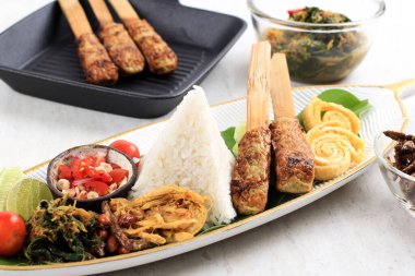 Nasi Kampüsü Bali. Çeşitli Tabaklar ve Birlikte Hizmet Verilen Popüler Bale Pirinç Yemeği. Bu menü Ayam Sisit, Sate Lilit, Saute Papaya Leaf ve Sambal Matah içerir..