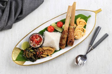 Üst Manzara Nasi Kampüsü Bali. Çeşitli Tabaklar ve Birlikte Hizmet Verilen Popüler Bale Pirinç Yemeği. Bu menü Ayam Sisit, Sate Lilit, Saute Papaya Leaf ve Sambal Matah içerir..