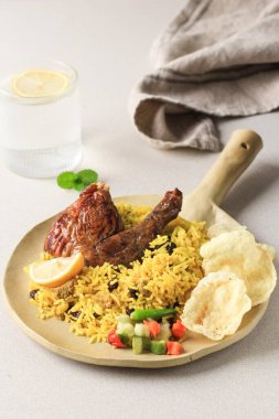 Krem Arkaplanda Kebuli Rice 'ın (Nasi Kabli veya Briyani) kaybedilmesi, üstüne kızarmış tavuk ve üzümlü üzüm konması.