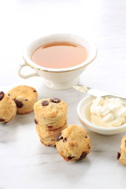 Pıhtılaşmış kremalı mini yuvarlak çörekler ve bir fincan çay, beyaz mermer arka plan 