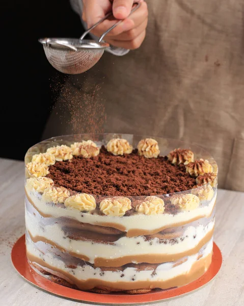 손으로 미무같은 케이크를 파우더와 넣는다 식탁에 케이크와 열매로 — 스톡 사진