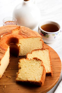 Yumuşak Vanilyalı Chiffon Keki ya da Tahta Tabakta Sünger Keki, Çay ve Bal ile servis edilir. Fırın için Parlak Yemek Fotoğrafçılığı Konsepti. Seçili Odaklanma 