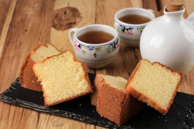 Yumuşak Vanilyalı Chiffon Keki ya da Tahta Tabakta Sünger Keki, Çay ve Bal ile servis edilir. Parlak Rustik Ahşap Yemek Fotoğrafçılığı Pastane Konsepti. 