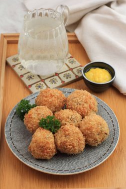 Undan, peynirden, ekmek kırıntısıyla sütle kaplanmış nefis ev yapımı Brulee bombası. Bitterballen Benziyor, Beyaz Tabakta servis ediliyor, Maydanozlu Ahşap Arkaplan Garnitür