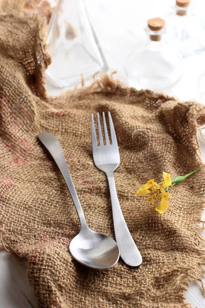 A Pair of Stainless Spoon and Fork on Jute Napkin