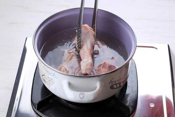 Indonesian Home Cooking Process, Female Hand Add Chicken Thigh Drumstick to the Pan using Tongs, Making Indonesian or Thai Style Curry, Traditional Asian Gourmet Called Opor Ayam, Gulai, Kari, or Kare