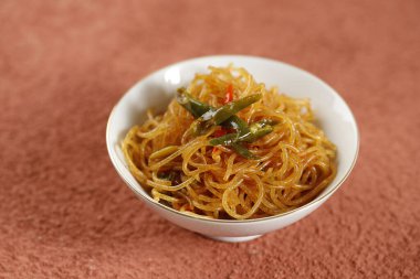 Kızarmış pirinç vermicalli ya da Bihun Goreng ile tatlı soya sosu ve biber karıştırın, beyaz kasede servis edilir.