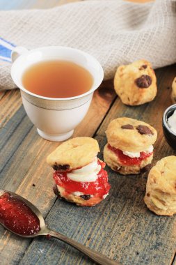 Reçelli çikolatalı çörekler, pıhtılaşmış krema ve Rustik ahşap masa üzerine çay.