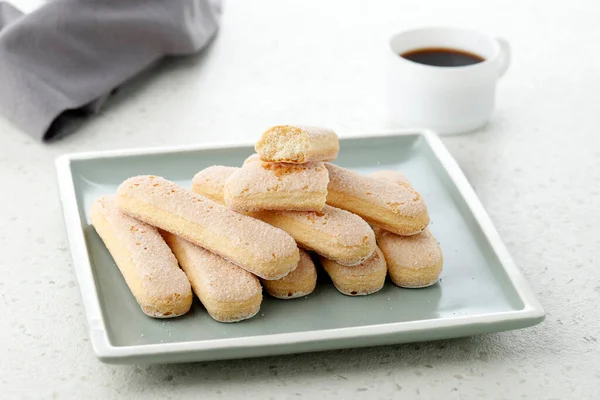 Italian Cookie Savoiardi and Cup of Coffee. Close up View of Ladyfinger Biscuit Cookie on Cream Concrete Table Background. Copy Space.