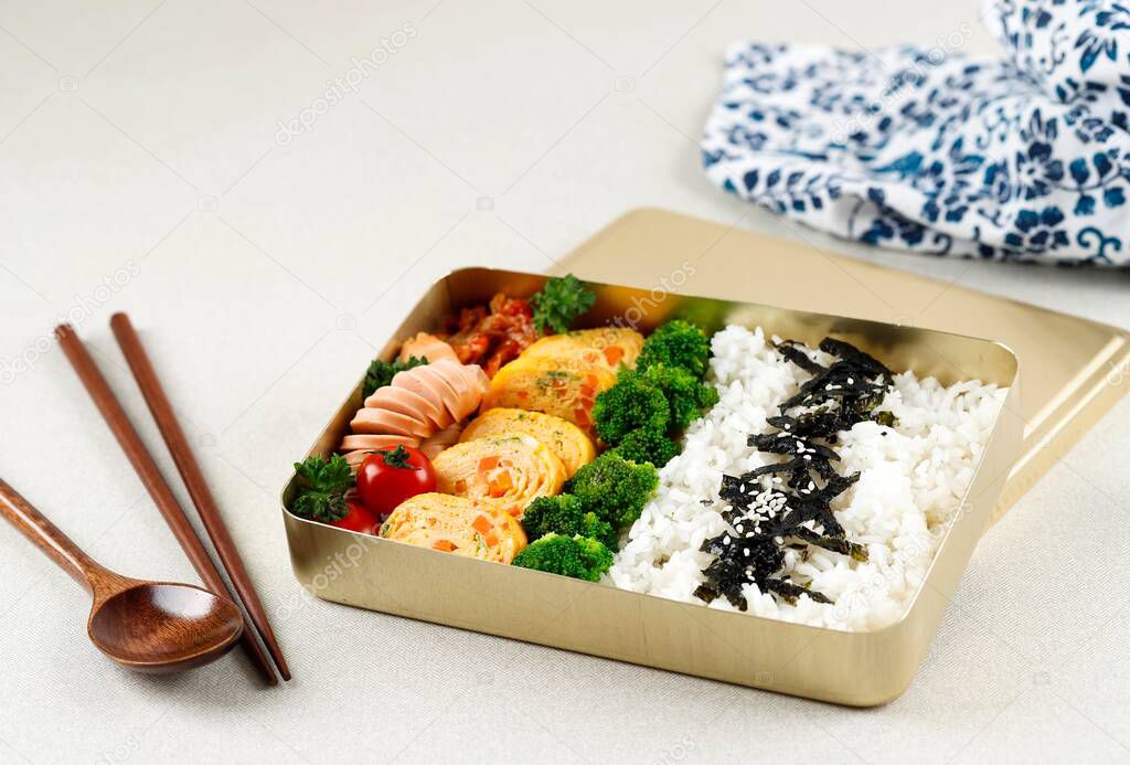 Korean Lunchbox Dosirak, Packed Meal Bento Lunchbox with various Banchan, Gyeran Mari, Tomato, Steamed Broccoli, Kimchi, and Sausage. 