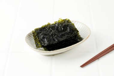 Crispy Salted Nori Laver Sheet on White Plate, Popular in Japan and Korea for Sushi and Kimbap. Copy Space for Text