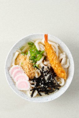 Top View Japanese Udon with Seafood Broth, Crispy Tempura, Green Onion, and Narutomaki Topping. Copy Space for Text