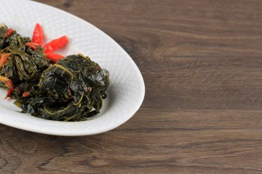 Buntil Daun Singkong, Stir Fry Cassava Leaves Stuffed with Grated Coconut, Petai Cina, and Salted Anchovy, Traditional Indonesian Daily Menu. Copy Space for Text 