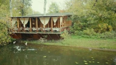 Autumn Park 'ta. Gölet ve ördekler. Sahildeki kafenin verandası. Sonbaharda bulutlu bir günde. Suda süzülen sonbahar yaprakları. 