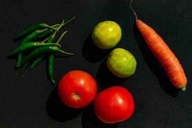 Domates, limon, yeşil biber ve havuç izole edilmiş siyah arka planda.