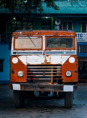 Terk edilmiş eski bir halk otobüsü açık alanda paslanıyor. Arkaplan bulanıklığı olan seçici odak.
