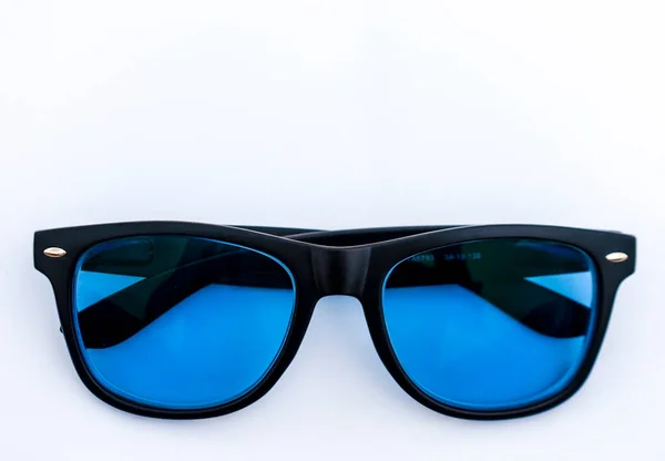 Stylish black sun-glass frame made of acetate material with blue shades on a white background. Selective Focus.