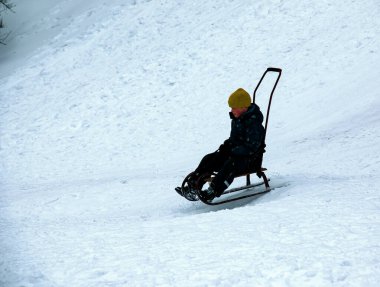 Dnepropetrovsk, Ukrayna - 12.31.2021: Küçük çocuk kışın kayarak kayıyor. Çocuklar için açık hava oyunu. Çocukluk, eğlence ve sezon konsepti.