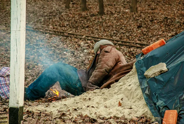 Homeless Man Lies Pile Sand Tries Keep Warm Man Lit — Stockfoto