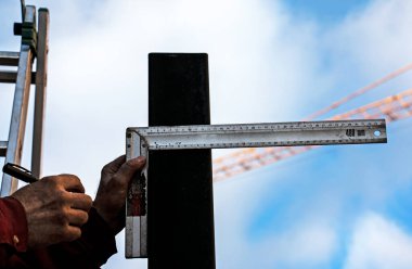 Yetenekli bir işçi ölçer ve demir cetvelle kare bir borunun üzerinde bir çizgi çizer..