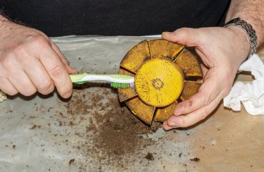 Kirli bir mutfak vantilatörünü fırçayla pislikten temizlemek. Bir adam vantilatörün parçalarını fırçayla temizler..